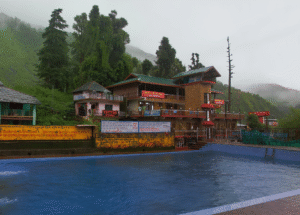 Bhagsu Waterfall flowing through rocks with Bhagsunath Temple nearby